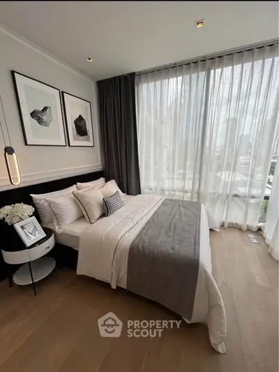 Luxurious bedroom with floor-to-ceiling windows and city view, featuring elegant decor and cozy bedding.