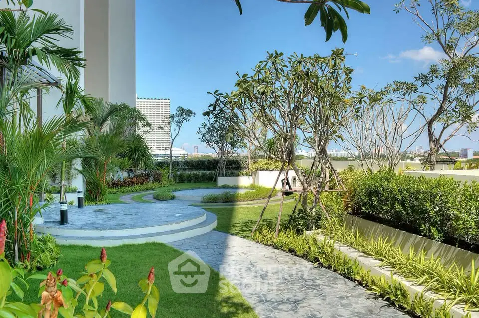 Lush garden area with paved walkway and vibrant greenery in modern residential complex.