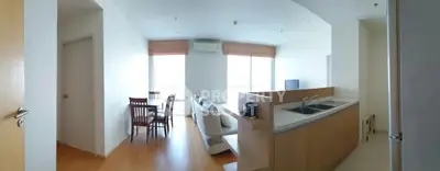 Spacious open-plan living room and kitchen with modern furnishings and large windows.