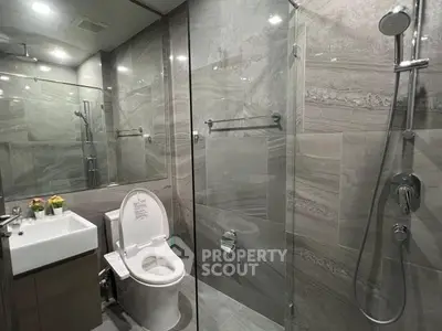 Modern bathroom with sleek gray tiles, glass shower, and contemporary fixtures.