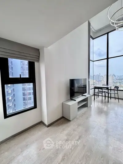 Modern living room with large windows offering stunning city views and stylish furniture.