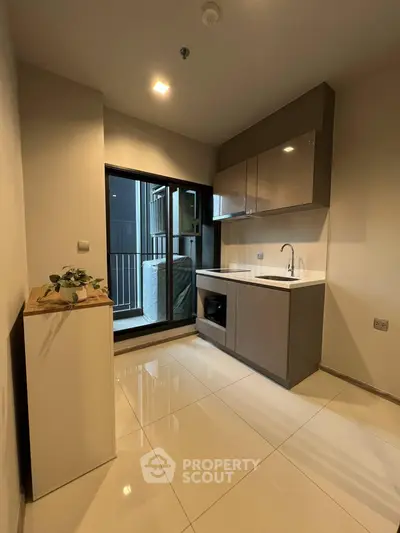 Modern kitchen with sleek cabinetry and balcony access, perfect for urban living.