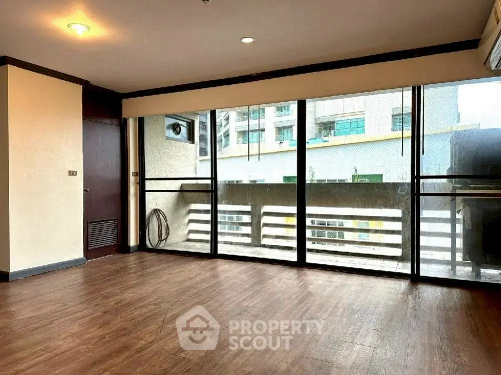 Spacious living room with large windows and wooden flooring in modern apartment.