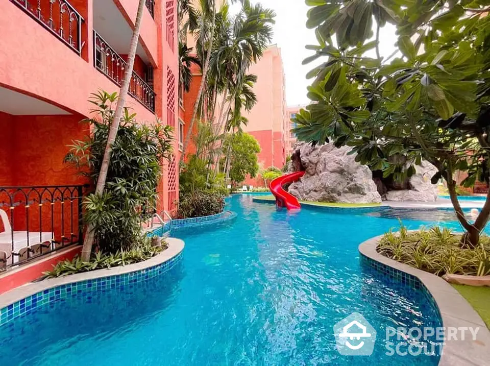 Luxurious resort-style pool with lush greenery and water slide, perfect for relaxation and leisure.