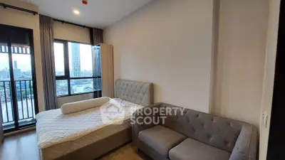 Modern bedroom with city view, featuring a cozy bed and stylish sofa, perfect for urban living.