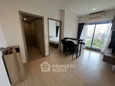 Modern apartment interior with open living space and city view from large window.
