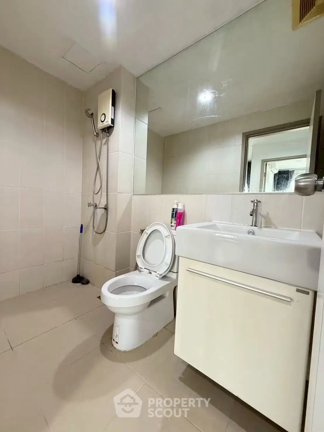 Modern bathroom with sleek fixtures and neutral tiles, featuring a shower and vanity unit.