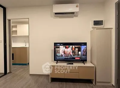 Modern living room with air conditioning and TV, open view to kitchen area.