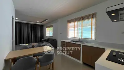 Modern open-plan living room and kitchen with sleek furniture and natural light.