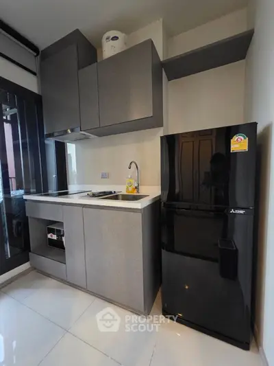 Modern kitchen with sleek cabinets and black fridge in compact layout