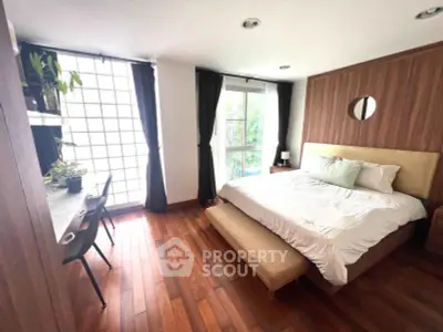 Spacious bedroom with wooden flooring and large windows for natural light