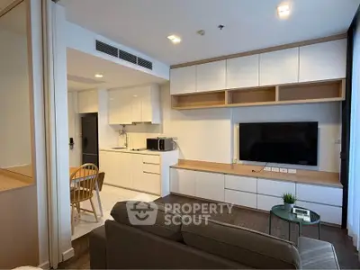 Modern living room with open kitchen, sleek cabinetry, and cozy seating area in a stylish apartment.