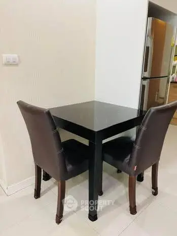 Cozy dining nook with sleek black table and modern chairs, adjacent to stainless steel fridge in stylish kitchen.