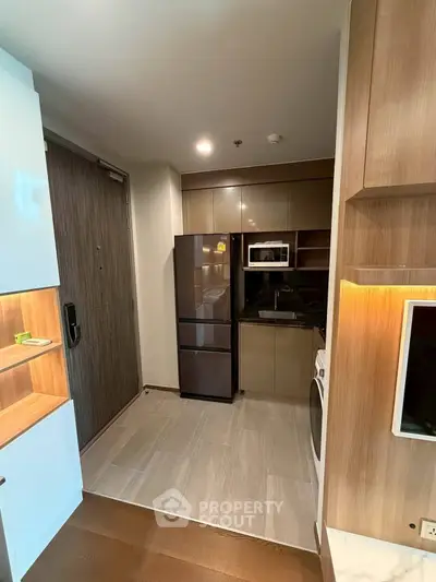 Modern kitchen with sleek appliances and wood cabinetry in a stylish apartment.