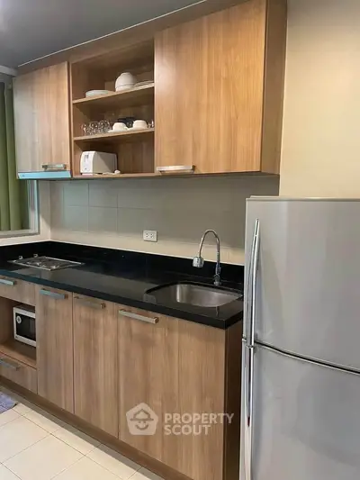 Modern kitchen with wooden cabinets, sleek black countertop, and stainless steel appliances.