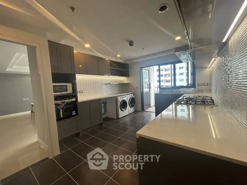 Modern kitchen with sleek cabinetry, gas stove, and built-in appliances in a high-rise apartment.