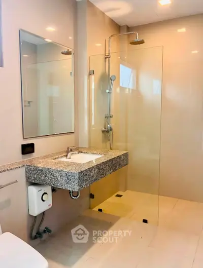 Modern bathroom with sleek shower and granite countertop in luxury apartment.