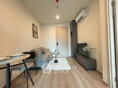 Modern living room with cozy sofa and TV, featuring stylish decor and wooden flooring.