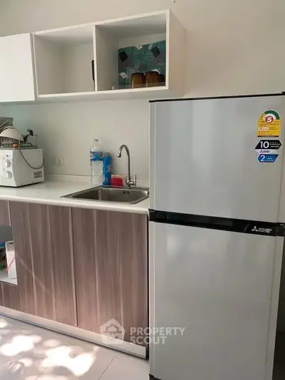 Modern kitchen with sleek cabinetry and stainless steel fridge in compact layout.