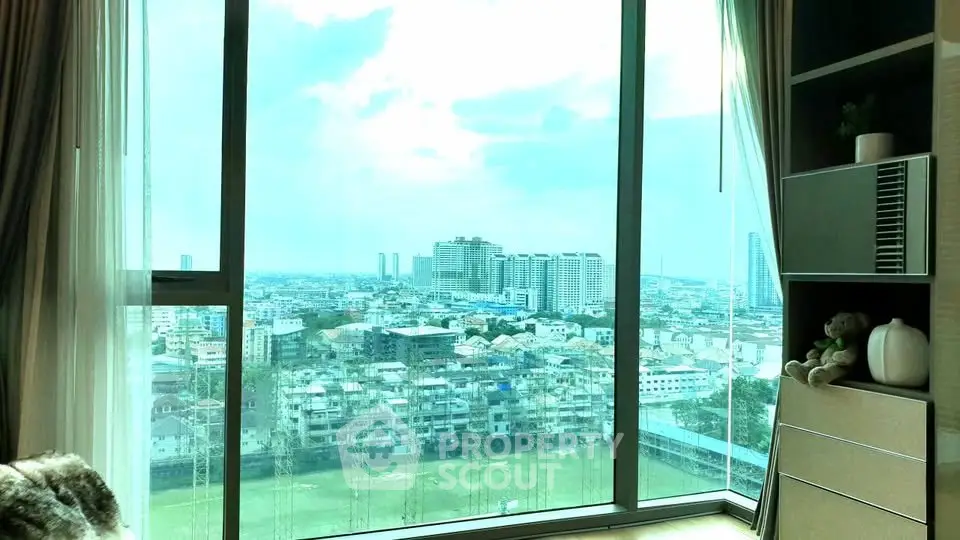 Stunning city view from a modern high-rise apartment with floor-to-ceiling windows.