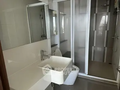 Modern bathroom with sleek fixtures and glass shower enclosure in a contemporary apartment.