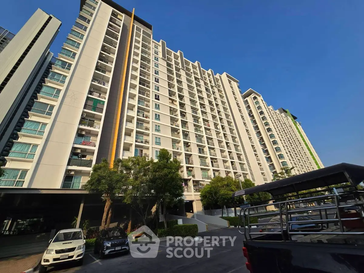 Modern high-rise residential building with spacious balconies and ample parking space.