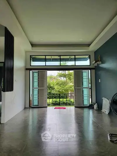 Spacious living room with large windows and garden view, perfect for natural light lovers.