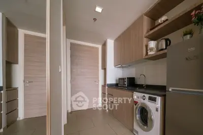 Modern kitchen with sleek cabinets, washing machine, and microwave in compact layout.