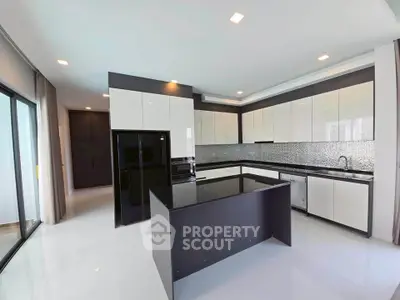 Modern kitchen with sleek black and white cabinetry and island, featuring open layout and ample natural light.