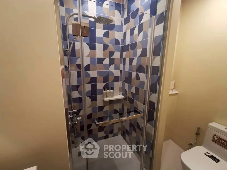 Modern bathroom with stylish geometric tile shower and sleek fixtures.