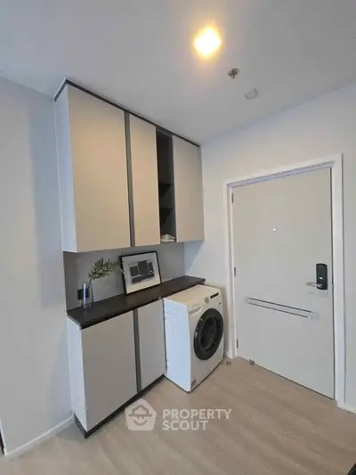 Modern laundry area with sleek cabinets and washing machine in a stylish apartment.