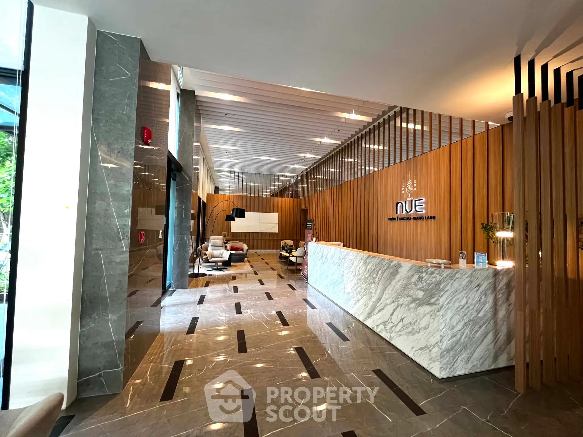Luxurious modern lobby with marble floors and stylish wooden accents in a high-end building.