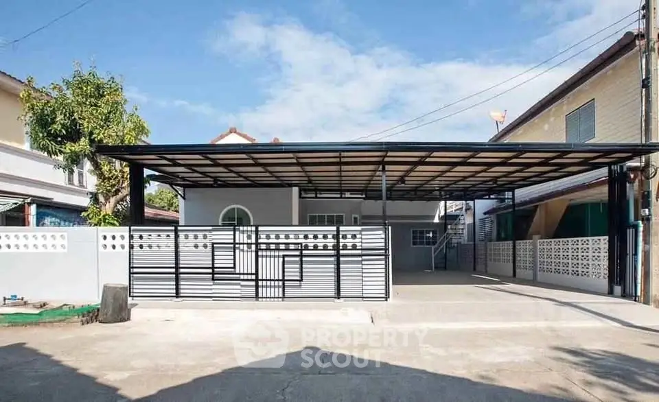 Modern single-story house with spacious carport and sleek metal gate design.