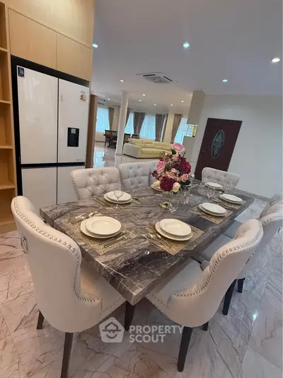 Luxurious dining area with elegant marble table and plush chairs in a spacious open-plan living space.