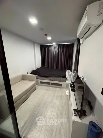 Modern compact bedroom with sleek design and air conditioning, featuring a cozy bed and sofa.