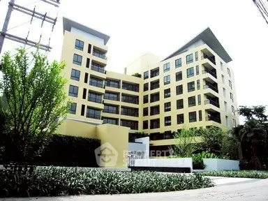 Modern multi-story apartment building with lush greenery and contemporary design.
