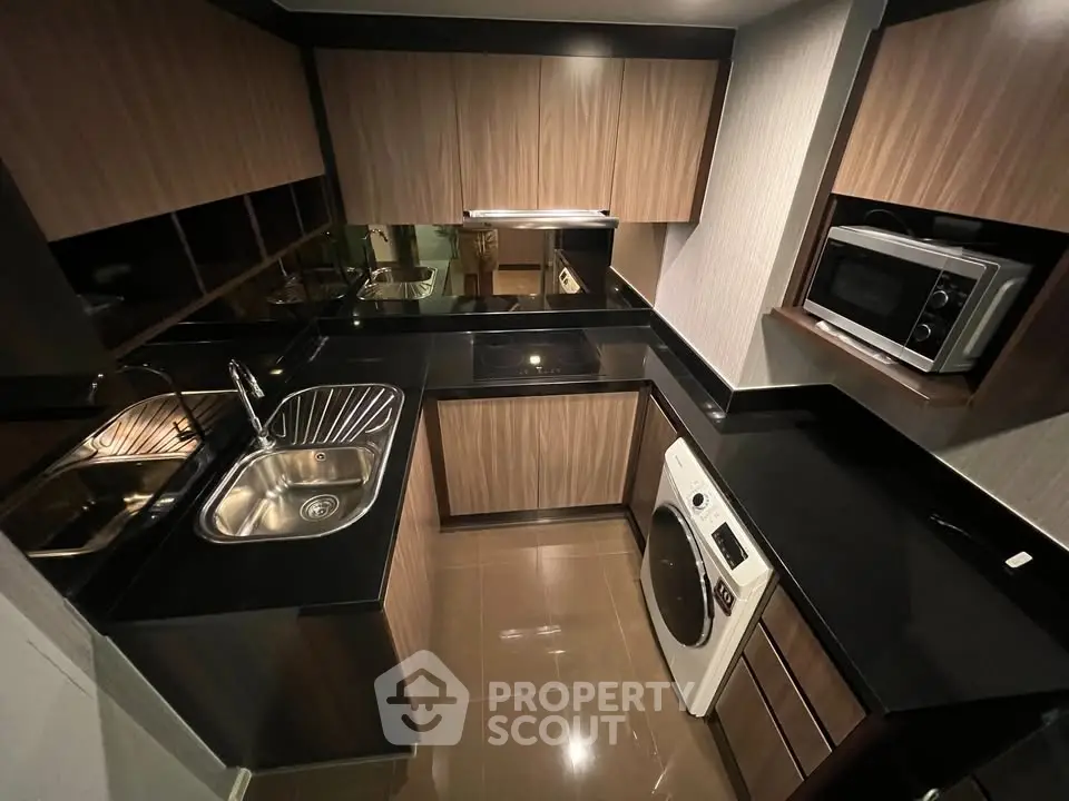 Modern kitchen with sleek black countertops, built-in appliances, and stylish wooden cabinetry.