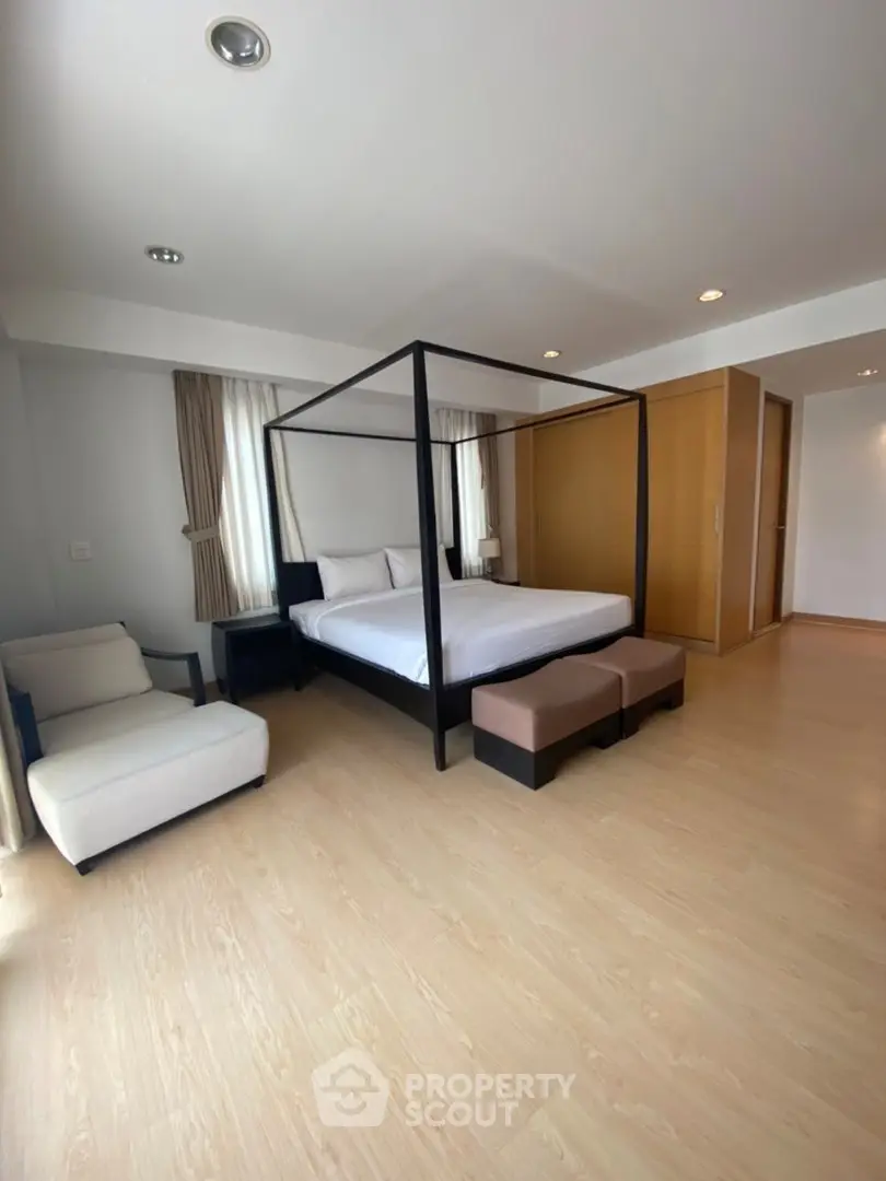 Spacious bedroom with modern four-poster bed and elegant decor
