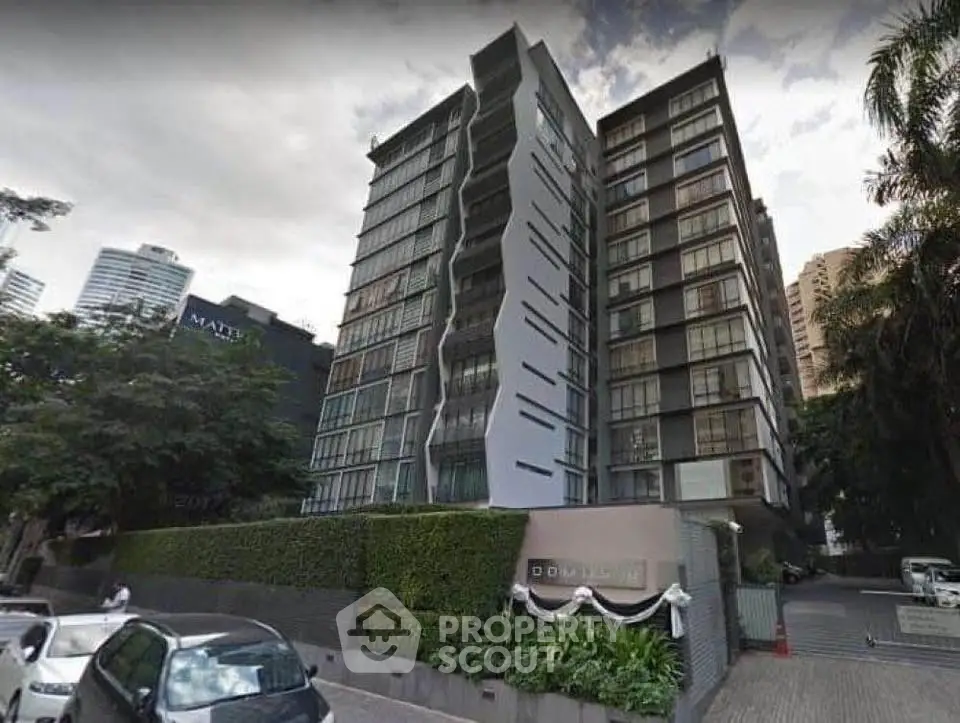 Modern high-rise residential building with sleek design and lush greenery in urban setting.