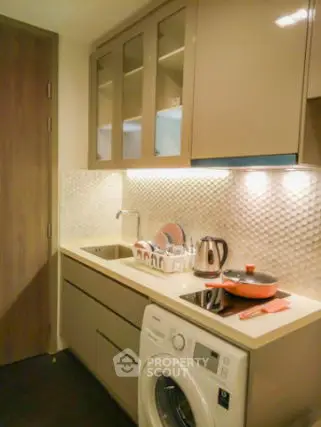 Modern kitchen with sleek cabinets, washing machine, and induction stove.