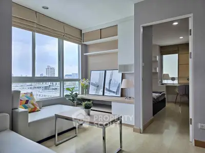 Modern living room with city view and cozy bedroom in open layout apartment.
