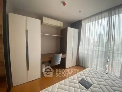 Modern bedroom with city view, featuring sleek furniture and ample natural light.