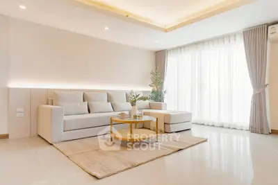 Elegant living room with modern sofa, soft lighting, and large window for natural light.