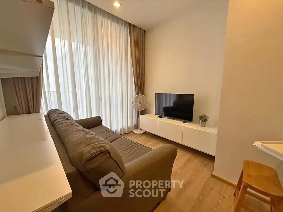 Cozy living room with modern decor, featuring a comfortable sofa, flat-screen TV, and elegant curtains.