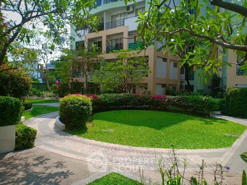 Charming garden view of modern residential building with lush greenery and winding pathway.