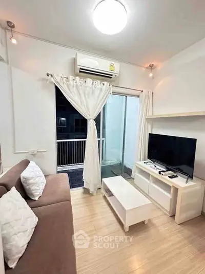 Cozy living room with modern decor, featuring a sofa, TV, and access to a small balcony.