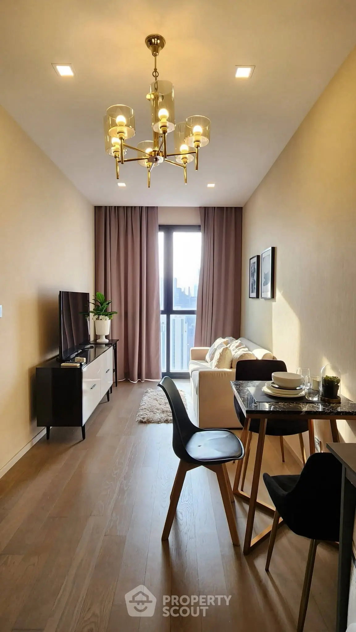 Stylish modern living room with elegant chandelier and cozy dining area, featuring a large window with city view.