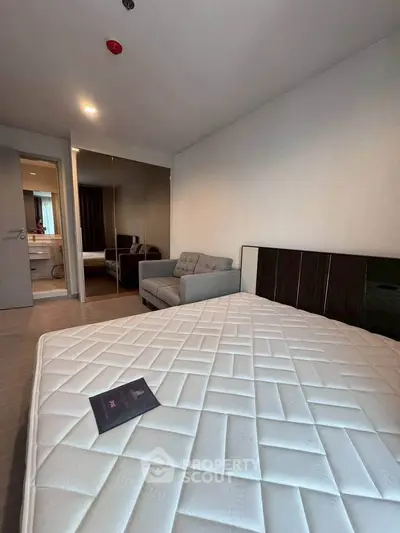 Modern bedroom with cozy sofa and mirrored wardrobe in a stylish apartment.
