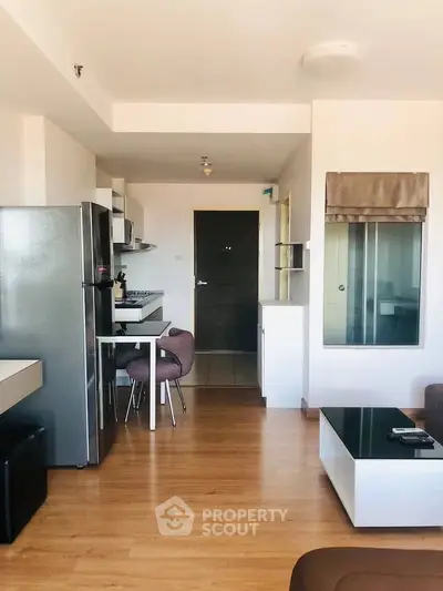 Modern open-layout kitchen and living area with sleek appliances and wooden flooring.