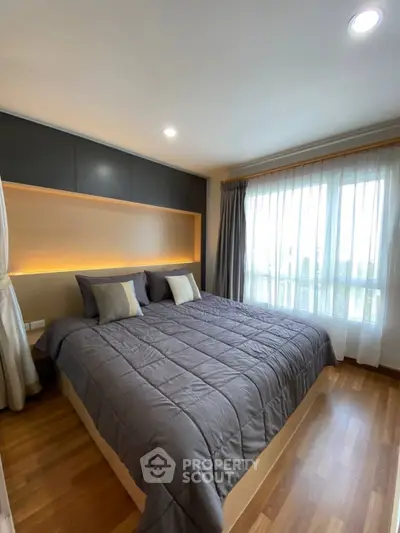 Modern bedroom with cozy lighting and large window in stylish apartment.